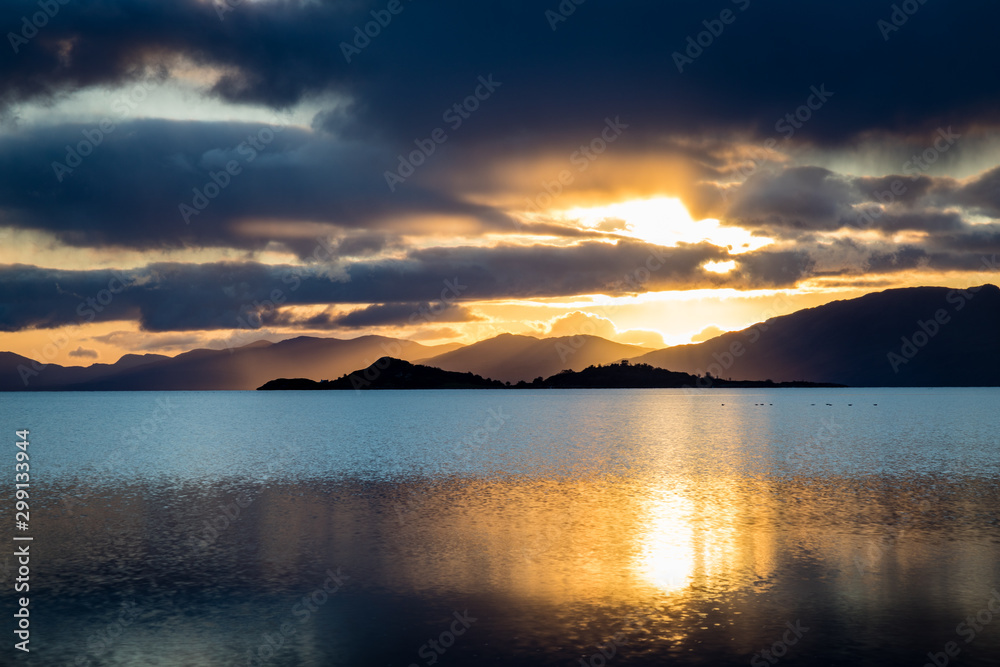 loch linnhe in the argyll region of the highlands of scotland during an autumn sunset showing golden light on the clouds and water and the islands of lismore and shuna