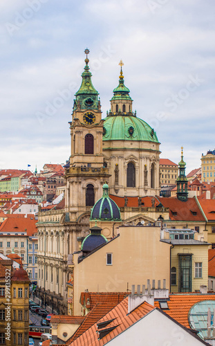 St. Nicholas baroque church above houses roofs in Prague, Czech Republic