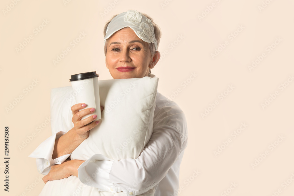 stylish beautiful aged woman with a short haircut with a pillow and a cup of coffee in her hands stylish beautiful aged woman with a short haircut with a pillow and a cup of coffee in her hands