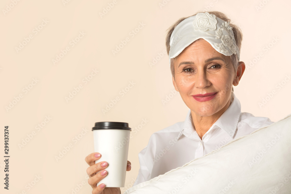 stylish beautiful aged woman with a short haircut with a pillow and a cup of coffee in her hands stylish beautiful aged woman with a short haircut with a pillow and a cup of coffee in her hands