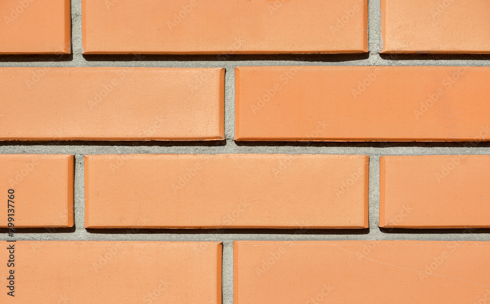 Obraz premium The texture of the wall of a new red brick house lit by the sun. Close-up. Background