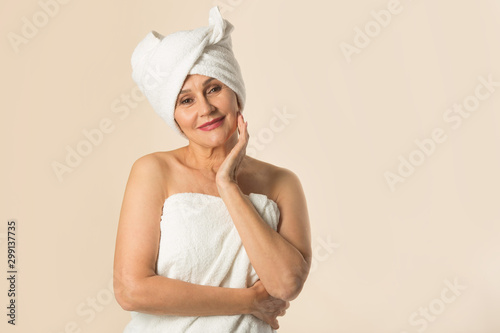 stylish beautiful aged woman in a white towel on a beige background
