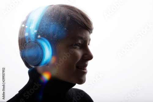 Beautiful boy in headphones listening music. White background. Blue neon light.