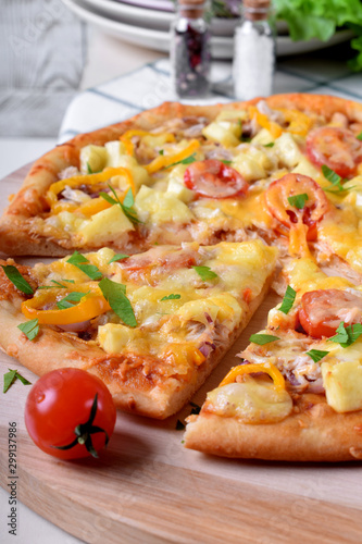 Pizza with chicken, cheese, tomatoes and bell peppers served on the round wooden board. Italian cuisine meal
