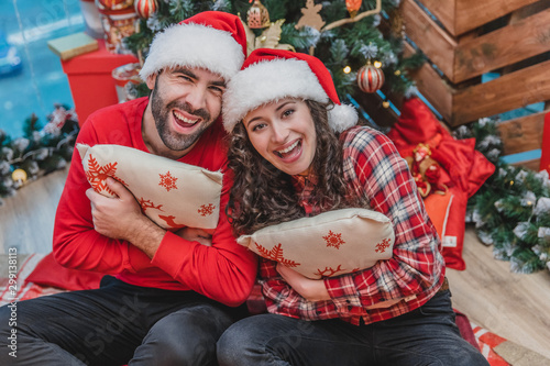 Cheerful women and men in red having fun while lights are sparkling on the christmas tree. photo