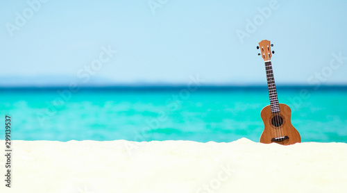 ukulele on the sand by the sea in summer photo