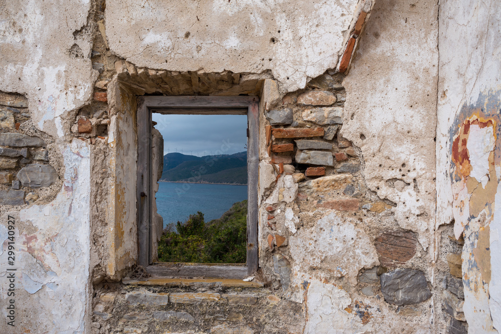 Old window overlooking the sea and mountains of the natural park