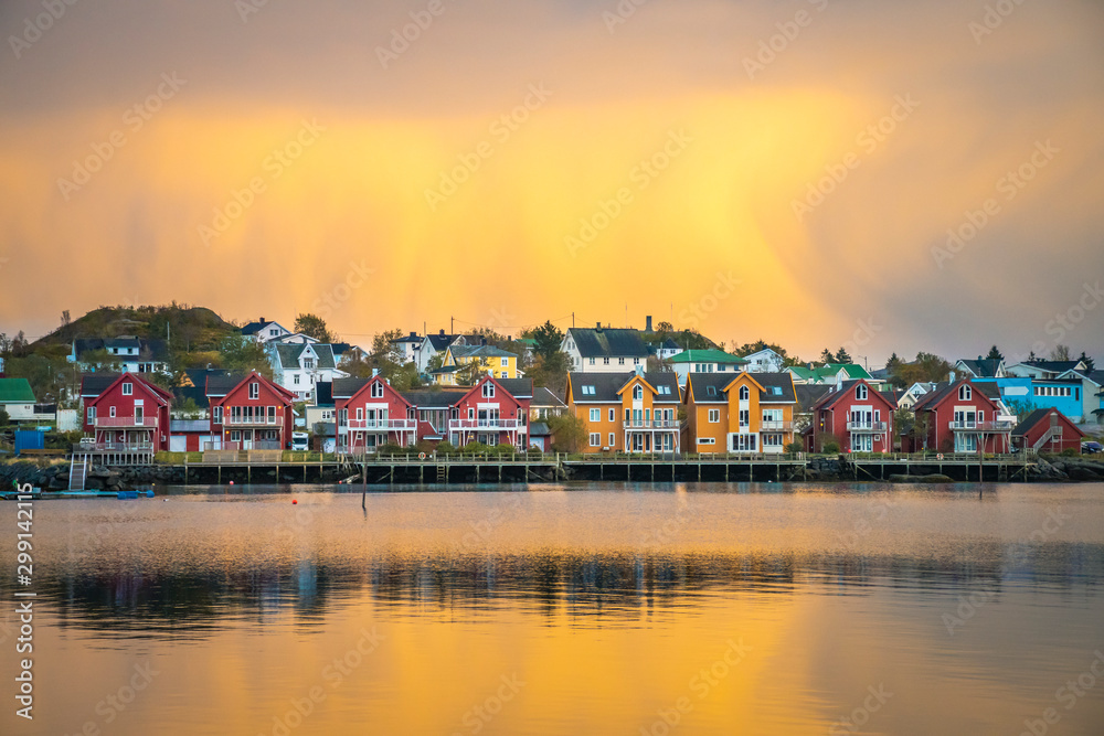 Apartment houses at the waterfront in Ballstad in front of yellow clouds at dawn