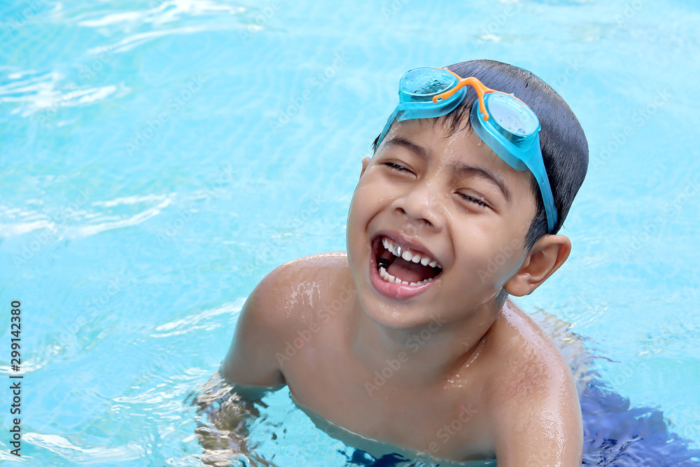 Close-up portrait of cute boy splashing in swimming pool having fun leisure activity.