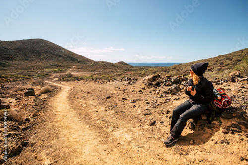 Active woman sit down on the rocks resting during a trekking activity in the mountains - ocean and sky in background  scenic place for healthy lifestyle people