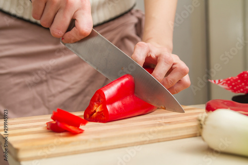 Chef slicing big, juicy, red paprika on a table