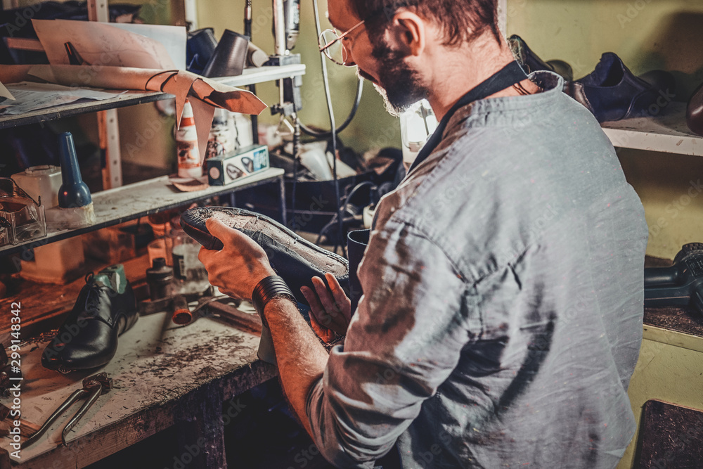 Experienced shoemaker is creating retro leather shoes at his comfortable workshop. Experienced shoemaker is creating retro leather shoes at his comfortable workshop.