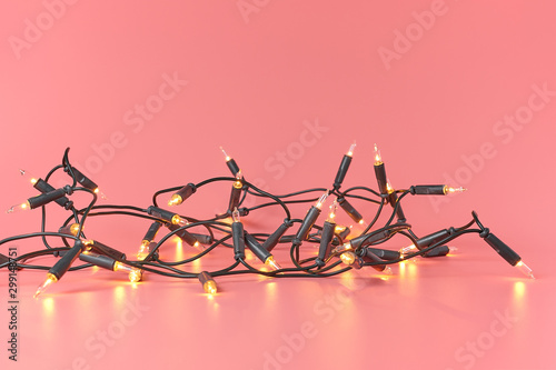 Christmas bright lights garland on a pink background with copy space.