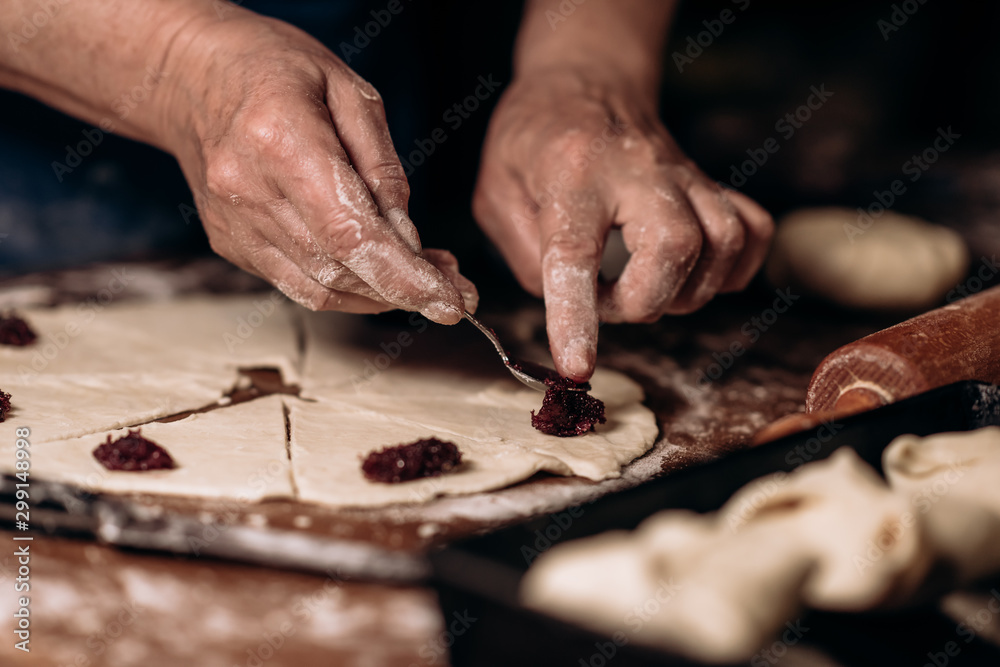 Obraz premium Housewife roll pieces of dough with plum jam