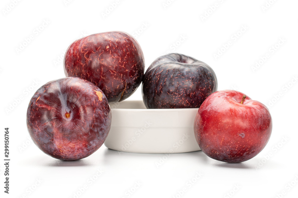 Obraz premium Group of four whole fresh red plum in ceramic stewpan isolated on white background