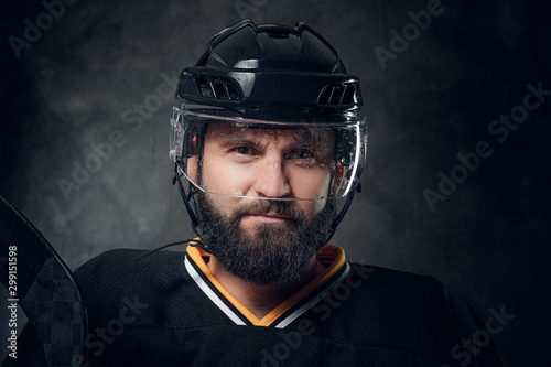 Portrait of brutal bearded man in hockey player uniform and helmet.