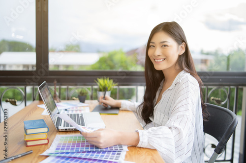 Asian Business women creative graphic designer working on laptop color selection,she drawing on Digital graphics tablet at a workplace,Photographer draw,retouching image,Color swatch samples design