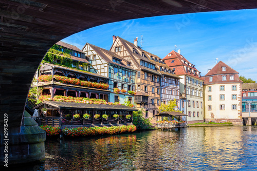 Typical half-timbered buildings with pastel facades lining the river Ill in the Petite France quarter in Strasbourg, France, seen from under the Saint-Martin bridge on a sunny morning.
