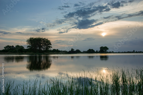 Sun behind the clouds above the lake