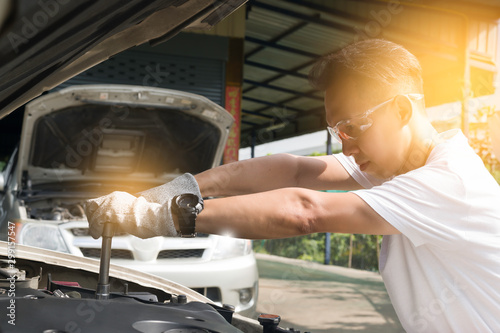 Hands of mechanic repairing the engine of the special keys (wrenches and ratchets). Professional mechanic in gloves working in a car service. photo