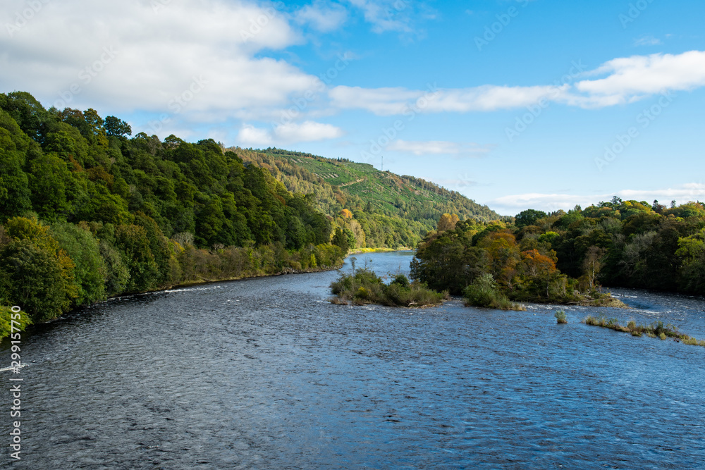 Scenic view of River Tay in autumn in Dunkeld and Birnham in Perthshire in Scotland. Fall panoramic river view in Scotland. Sunny day, blue sky, October.