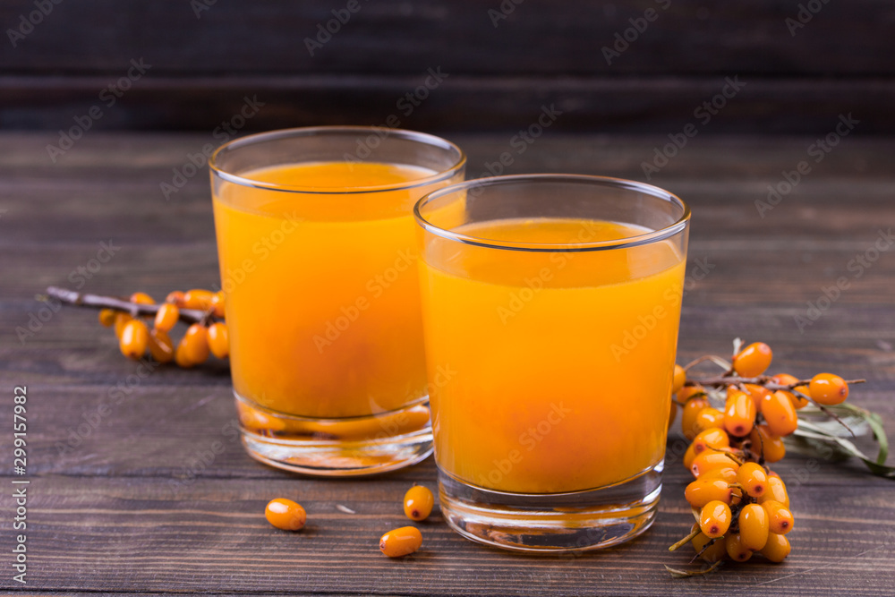 Glass of juice and branches of orange sea buckthorn Glass of juice and branches of orange sea buckthorn