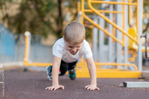 Kid boy working out on the floor, doing push-ups on the Playground