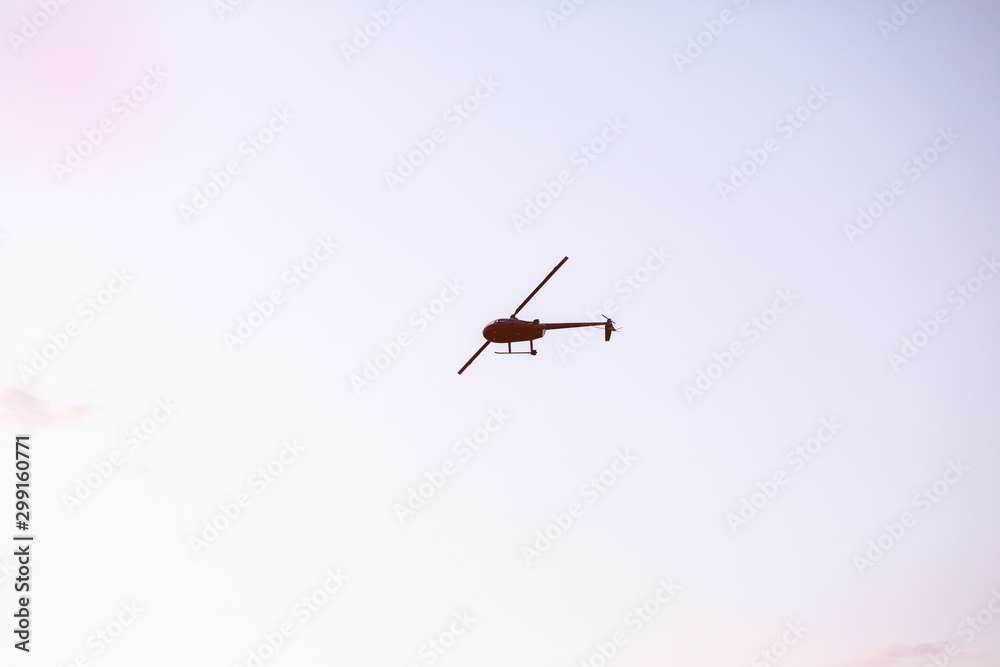 Silhouette of a chopper high in the blue sky seen from below, the military maneuvers; worm’s eye view. Silhouette of a chopper high in the blue sky seen from below, the military maneuvers; worm’s eye view.