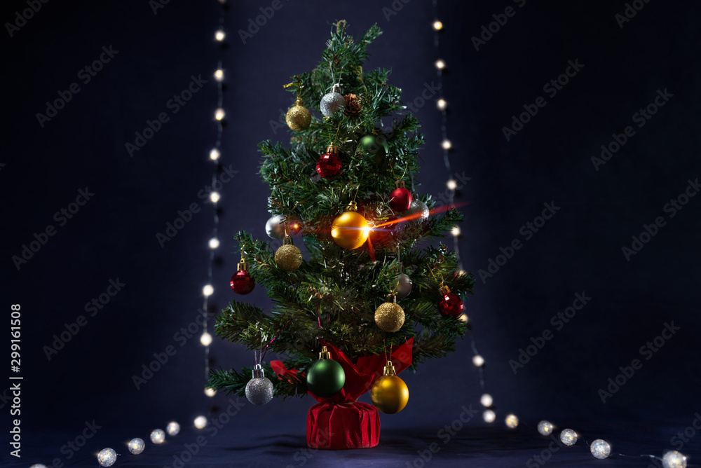 There is xmas tree with different colors ball between the glowing lights like runway. It is on the black background. Merry Christmas. Happy New Year 2020. There is xmas tree with different colors ball between the glowing lights like runway. It is on the black background. Merry Christmas. Happy New Year 2020.