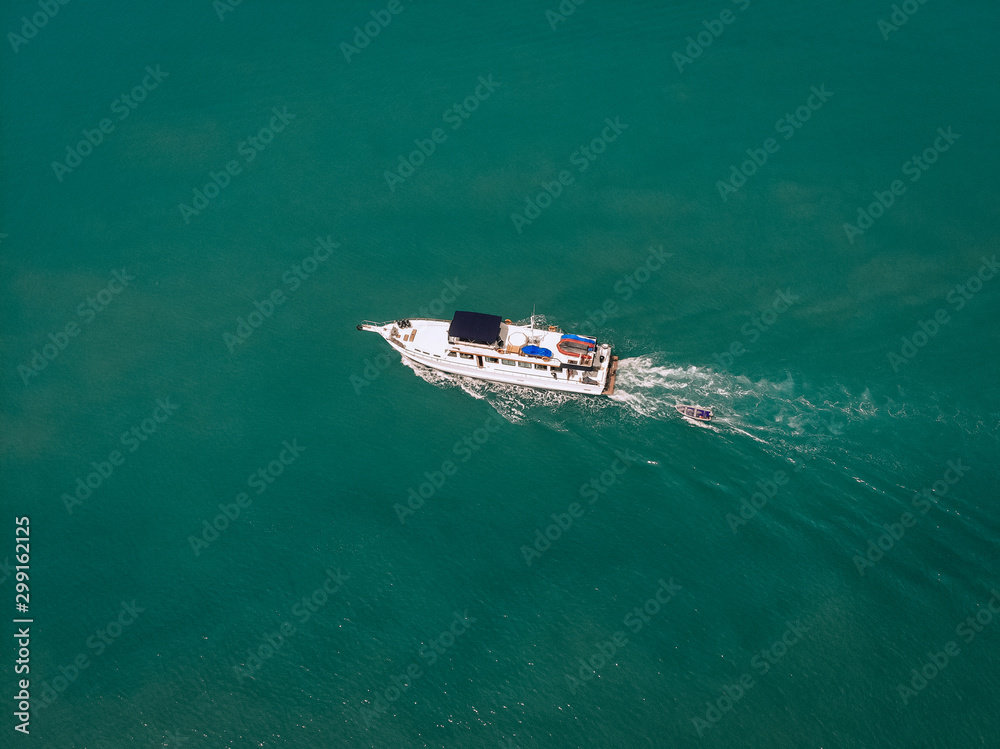 Aerial view of the speedboat and a boat behind it sailing near the coast of Thailand, white trace on the water; vessels concept.