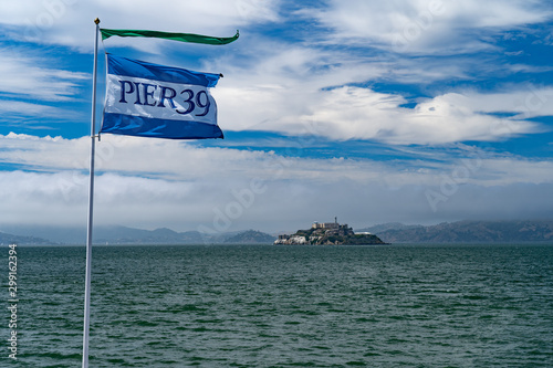Photography A flag flies in the foreground near the bay with an island in the distance