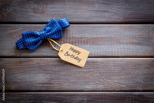 Men's birthday concept. Happy birthday text and bow tie on dark wooden background top view copy space photo