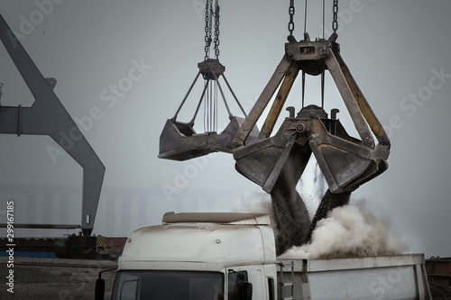 Fotografía Grapple crane unloading cement clinker from ship to truck in river port