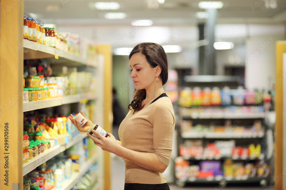 Woman who chooses products in the supermarket. Read product information.Concept of healthy food, bio, vegetarian, diet.
