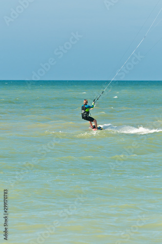 Front view, long distance of a single, young male, moving over tropical water  by a kite board off the coast of the gulf of Mexico on a sunny, winter day