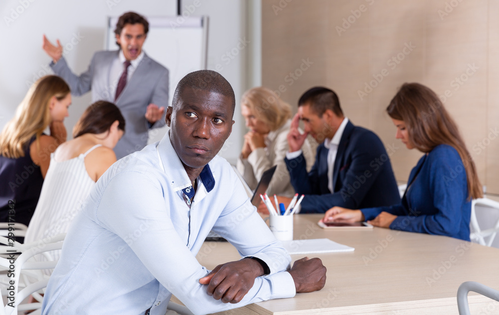 Frustrated African man with colleagues scolded by boss