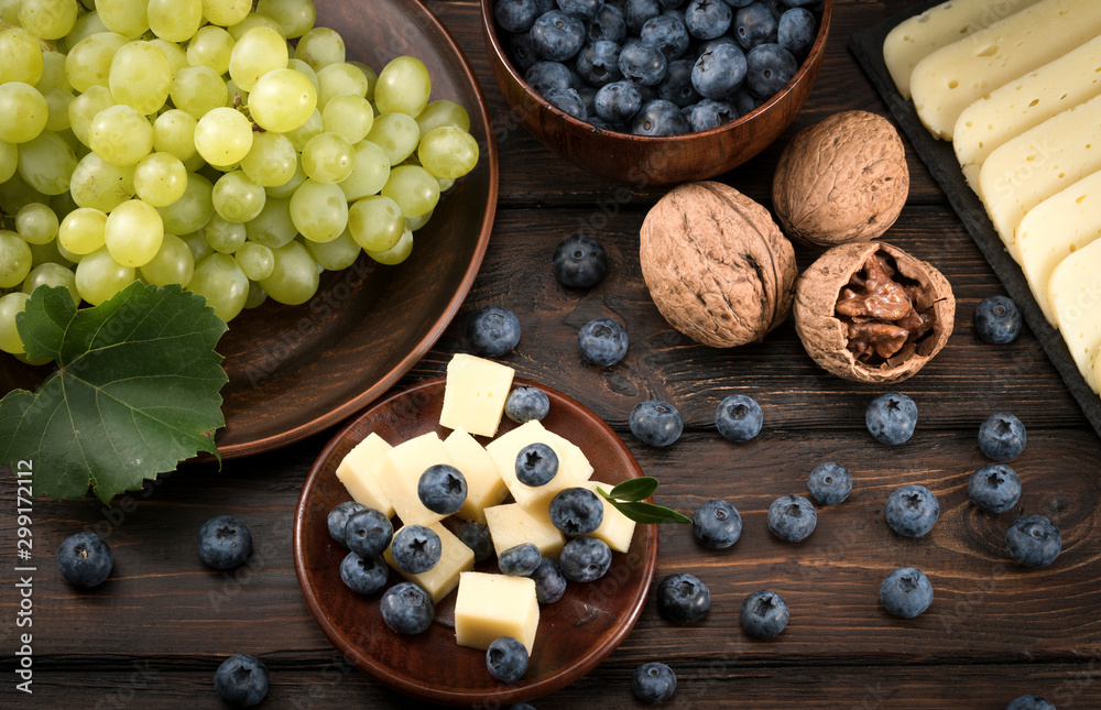 blueberry grapes and cheese on a wooden background blueberry grapes and cheese on a wooden background