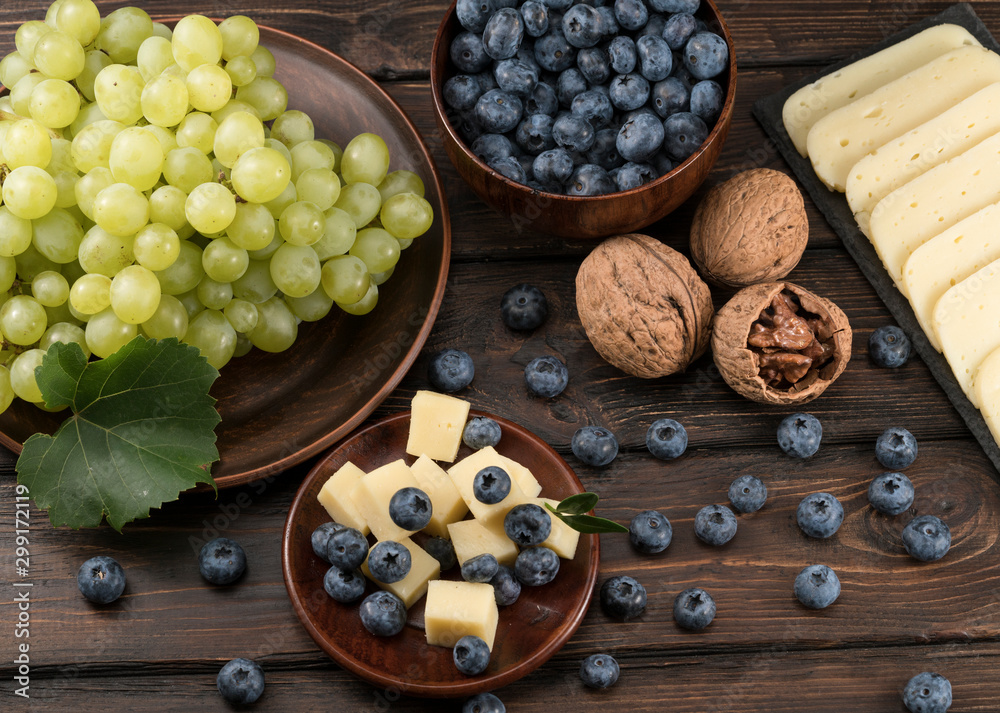 blueberry grapes and cheese on a wooden background
