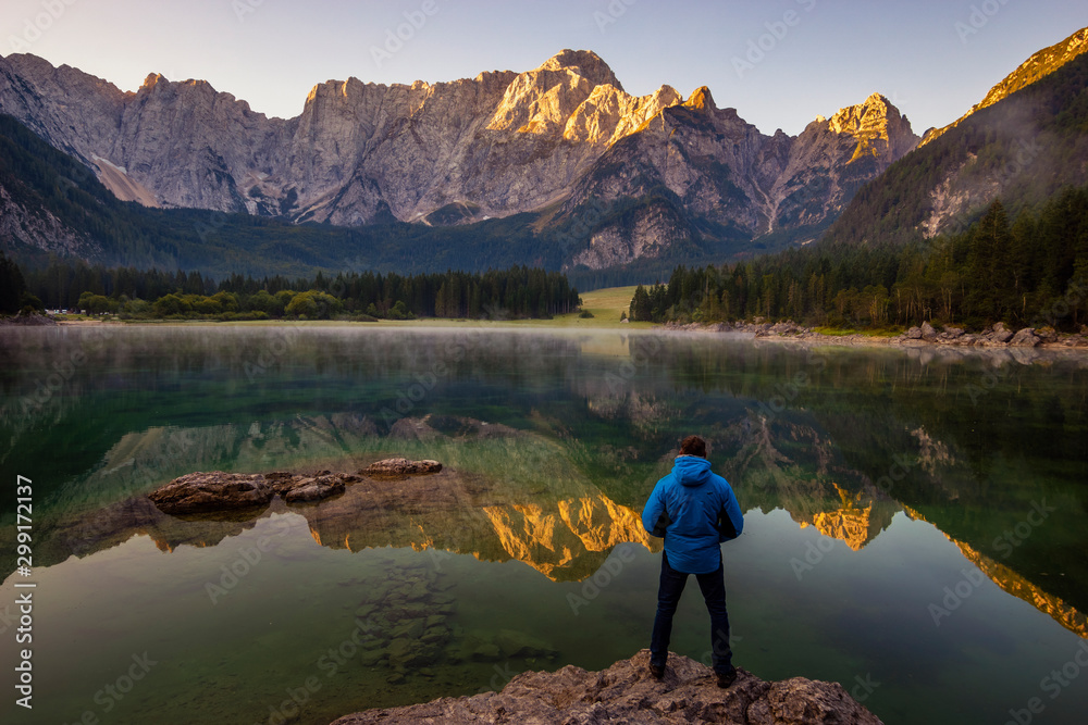 traveler admiring the alpine lake during sunrise