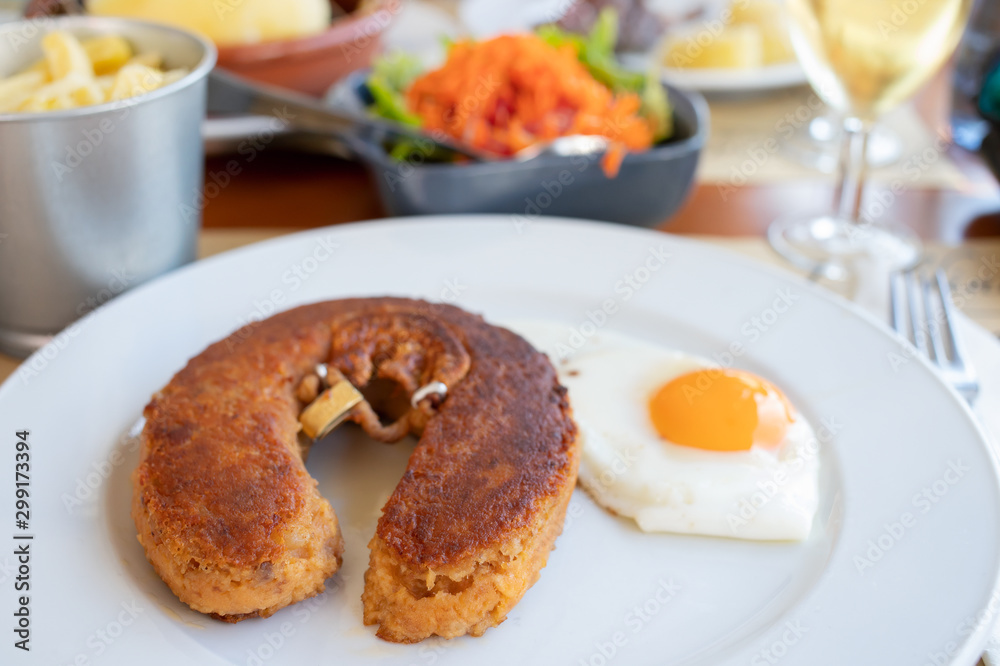 typical smoked sausage alheira with egg in white dish in restaurant typical smoked sausage alheira with egg in white dish in restaurant
