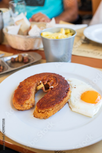 typical smoked sausage alheira with egg in white dish in restaurant