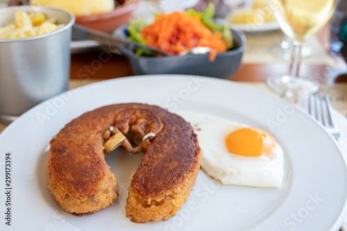 typical smoked sausage alheira with egg in white dish in restaurant