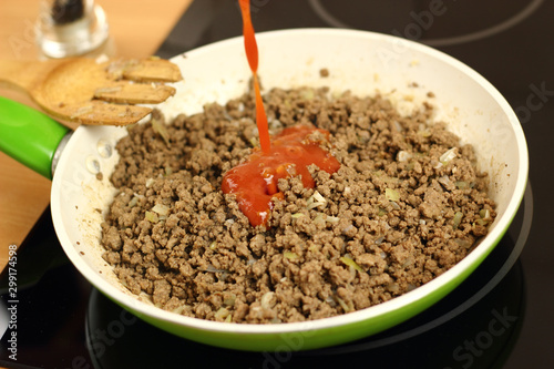 Pouring chilli sauce into ground beef