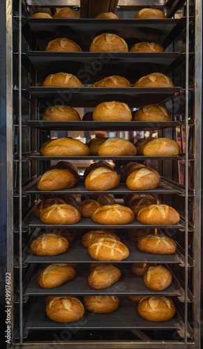 Freshly baked bread loaves on tray track trolley. Metal shelves with bread buns