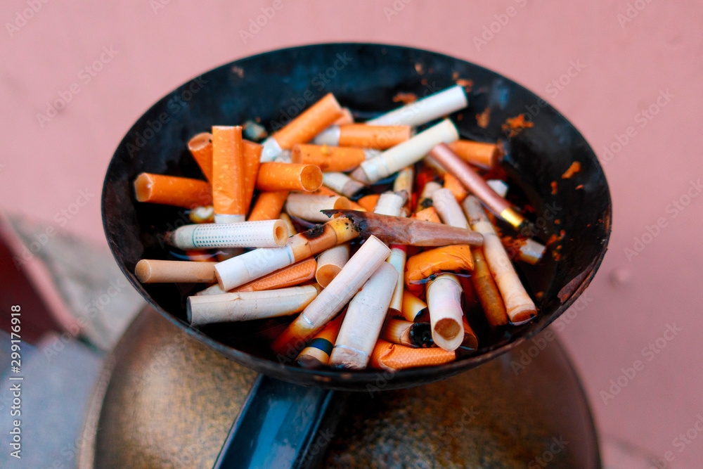 cigarette butts filled with water in a street ashtray cigarette butts filled with water in a street ashtray
