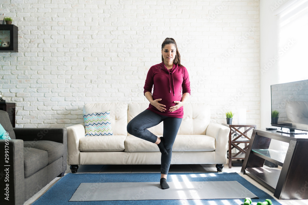 Caucasian Pregnant Woman Exercising On Mat At Home