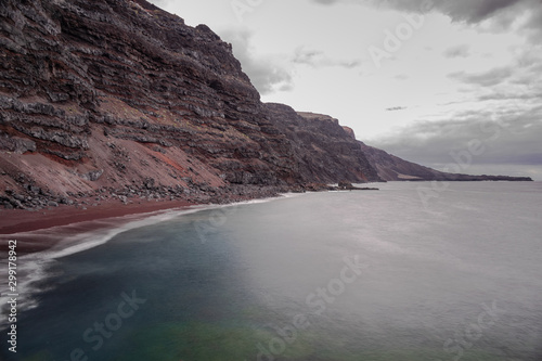 Verodal beach, red volcanic sand beach, long exposure photography, grey clouds sky,  Atlantic ocean, El Hierro, Canary islands, Spain photo