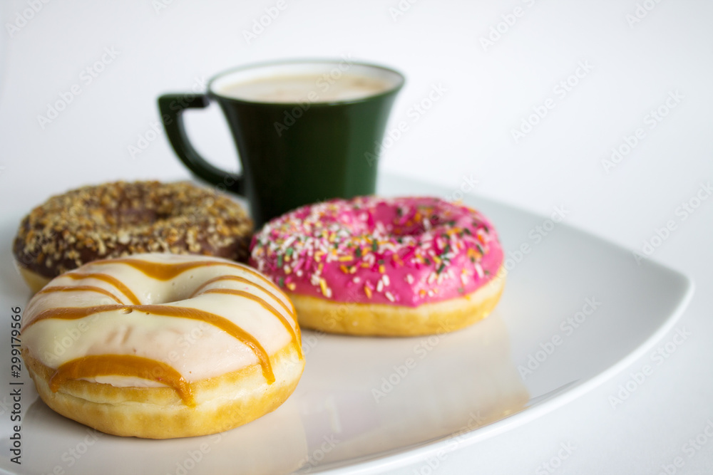 Fresh colorful donuts on a white plate and a Cup of coffee Fresh colorful donuts on a white plate and a Cup of coffee