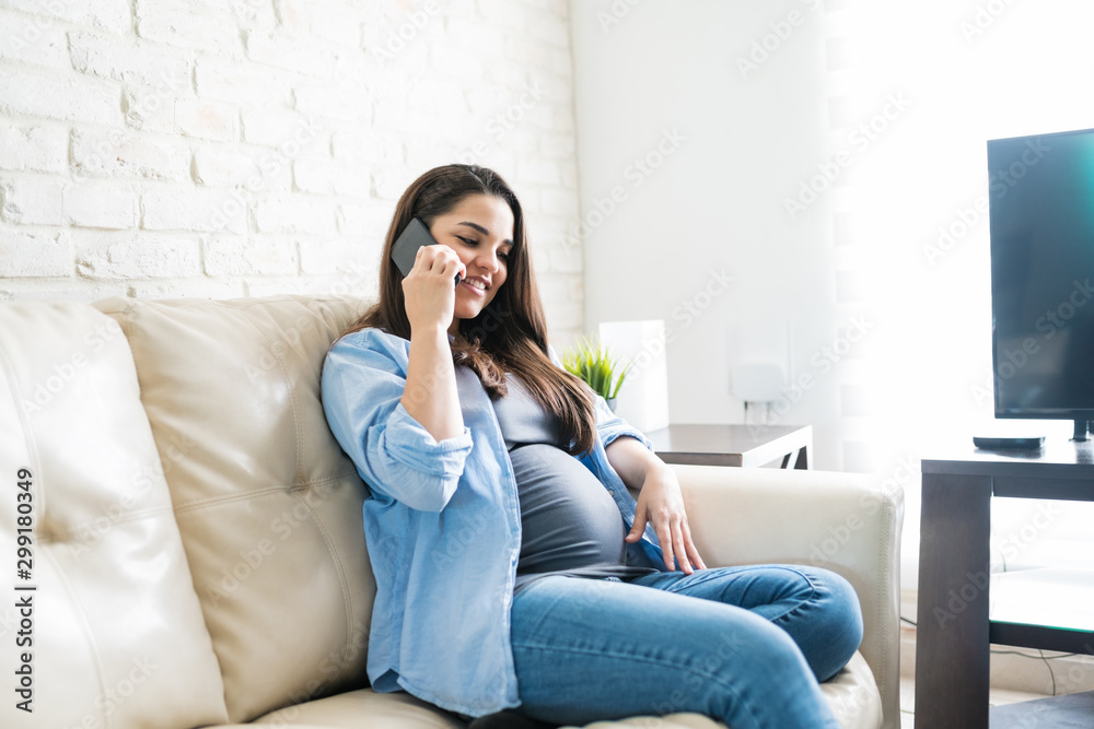 Attractive Expectant Female With Smartphone On Sofa