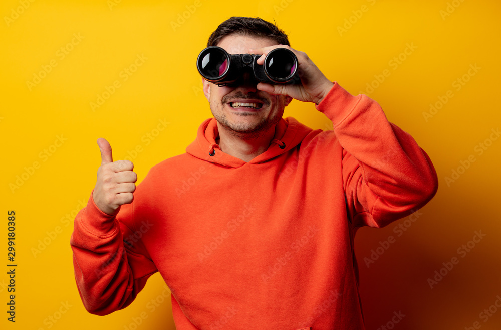 Handsome man with binocular on yellow background Handsome man with binocular on yellow background